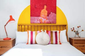A bed with a yellow headboard, striped pillows, and a white pillow.