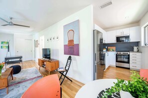 A modern kitchen with white cabinets, a black stove, and a stainless steel refrigerator.