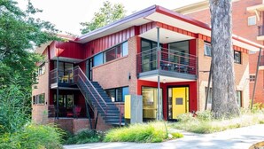 A modern building with a red and white facade, a balcony, and a staircase leading to an upper level. - Modern Marvels (Atlanta)