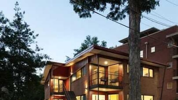 A modern two-story building with large windows, a balcony, and a visible staircase. - Modern Marvels (Atlanta)