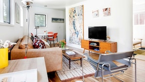 A modern living room with a sofa, coffee table, and a TV on a wooden cabinet. - Modern Marvels (Atlanta)