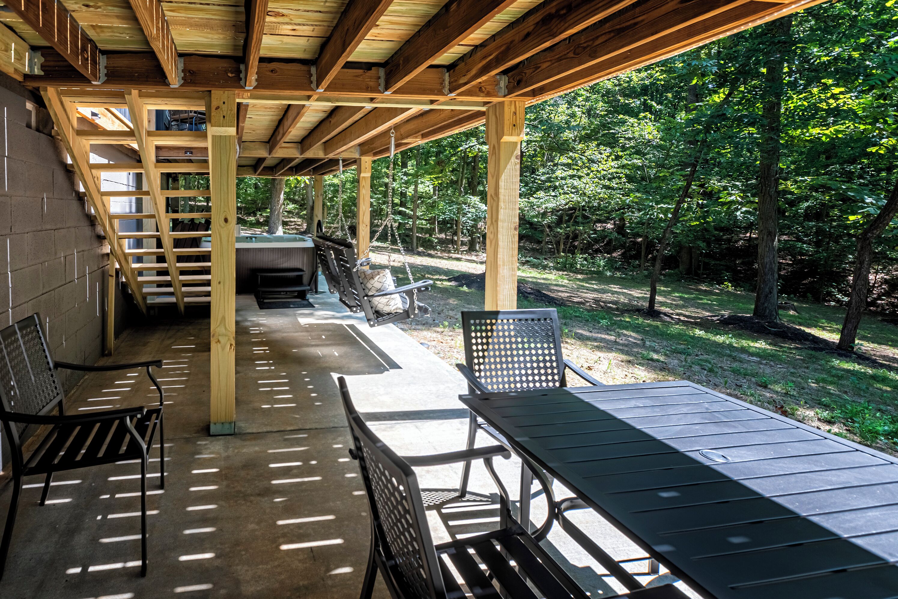 Un'area patio coperta con tavolo e sedie, un'amaca e un angolo barbecue.