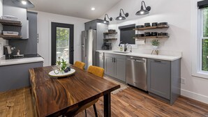A modern kitchen with grey cabinets, stainless steel appliances, and a wooden dining table.