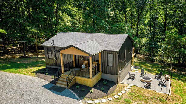 A cabin with a porch, outdoor seating, and a small deck.