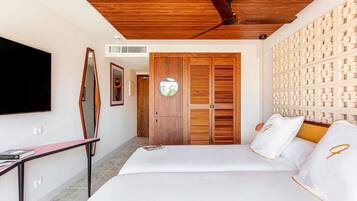 Un dormitorio moderno con techo de madera, ventilador de techo, cama con ropa blanca, televisor montado en la pared y armario con espejo.