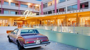 Een klassiek hotel met een oldtimer ervoor geparkeerd.