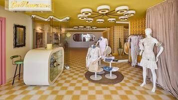 Una boutique con maniquíes mostrando vestidos, un mostrador de estilo vintage y un suelo a cuadros.