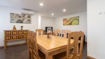 A dining area with a wooden table and chairs, a small cabinet with drawers, and two wall-mounted paintings.