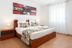A modern bedroom with a wooden bed, a nightstand with a lamp, and a large abstract painting on the wall. - Casa da Petisqueira 88, Paredes - O Porto  (Paredes)