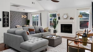 A modern living room with a grey sectional sofa, a fireplace, and a ceiling fan.