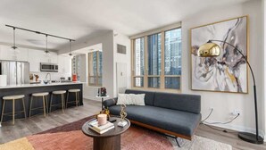 Een moderne woonruimte met een keuken, eethoek en een groot raam met uitzicht op de stad.