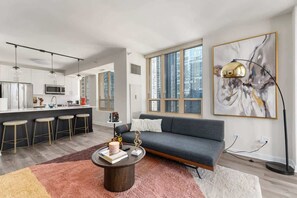 Un espacio habitable moderno con cocina, comedor y un amplio ventanal con vistas a la ciudad.