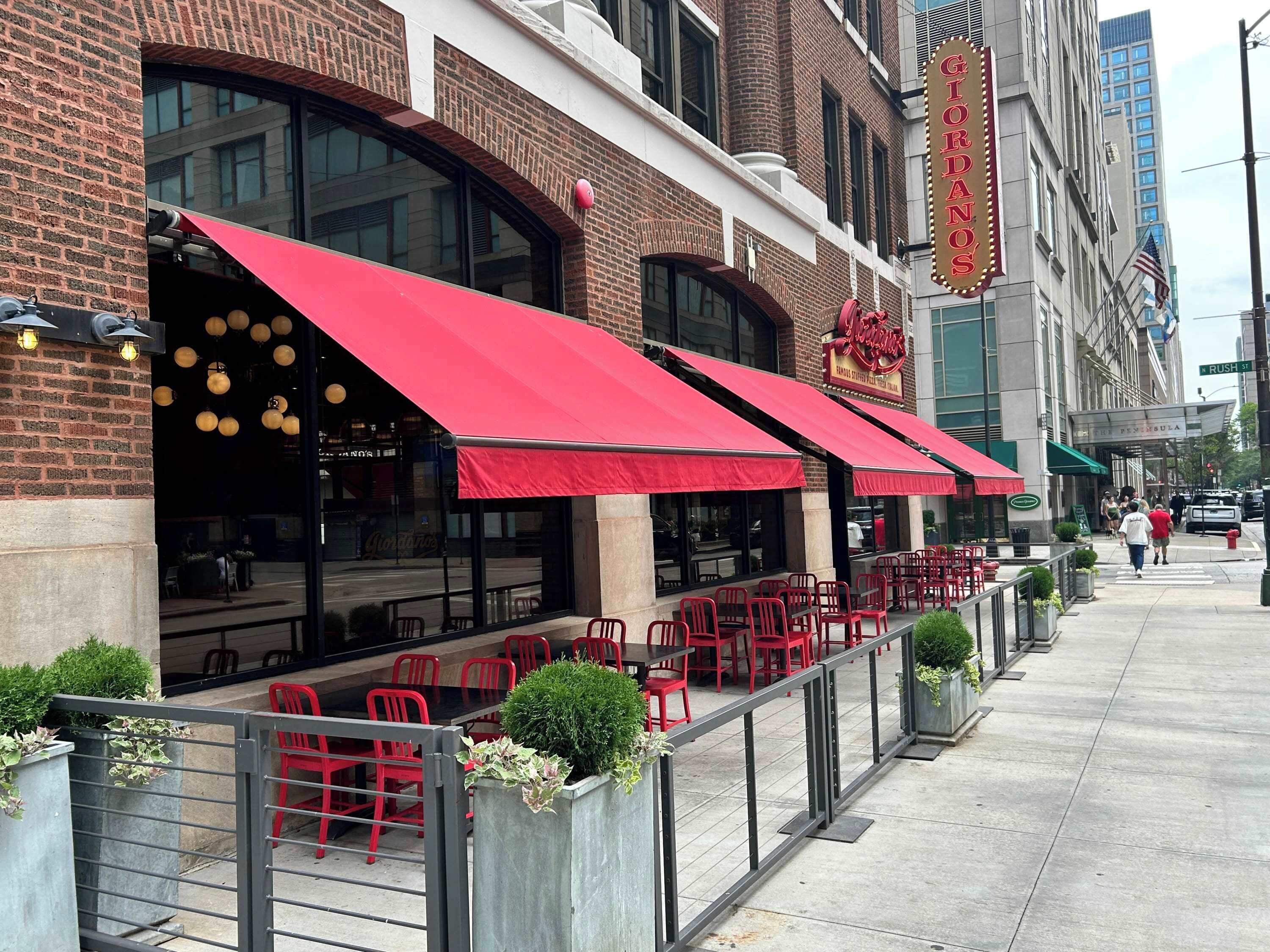 A restaurant with red awnings and outdoor seating.
