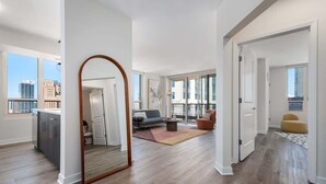 Een ruime woonkamer met een grote spiegel, een bank, een salontafel en uitzicht op de stad.