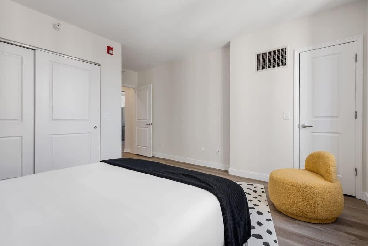 A bedroom with a bed, a wardrobe, a chair, and a door.