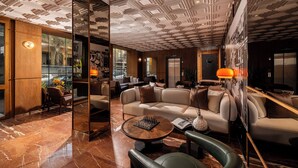 Un salon spacieux avec un plafond haut, un grand canapé, une table basse et un jeu d’échecs.