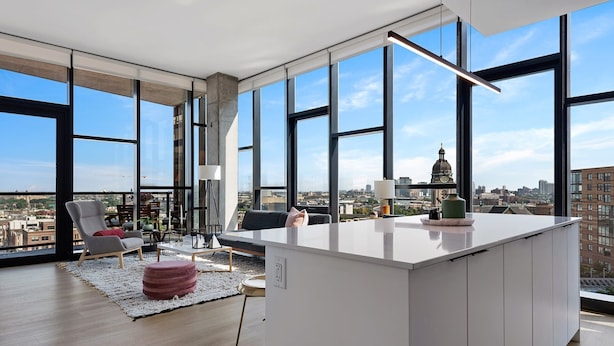 Eine moderne K üche mit großen Fenstern, einer zentralen Kochinsel und Blick auf die Stadtlandschaft.
