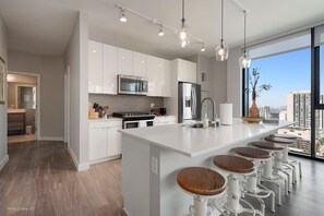 A modern kitchen with white cabinets, stainless steel appliances, and a large island with bar stools.