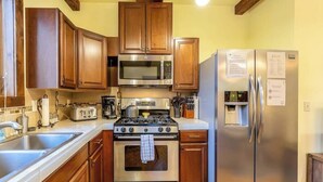 A kitchen with wooden cabinets, a stainless steel stove, a microwave, and a refrigerator. - Cozy Pet-Friendly Cottage Near Downtown Bend (Bend)