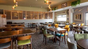 Un restaurant avec des tables et des chaises en bois, un sol en briques et des lampes suspendues.