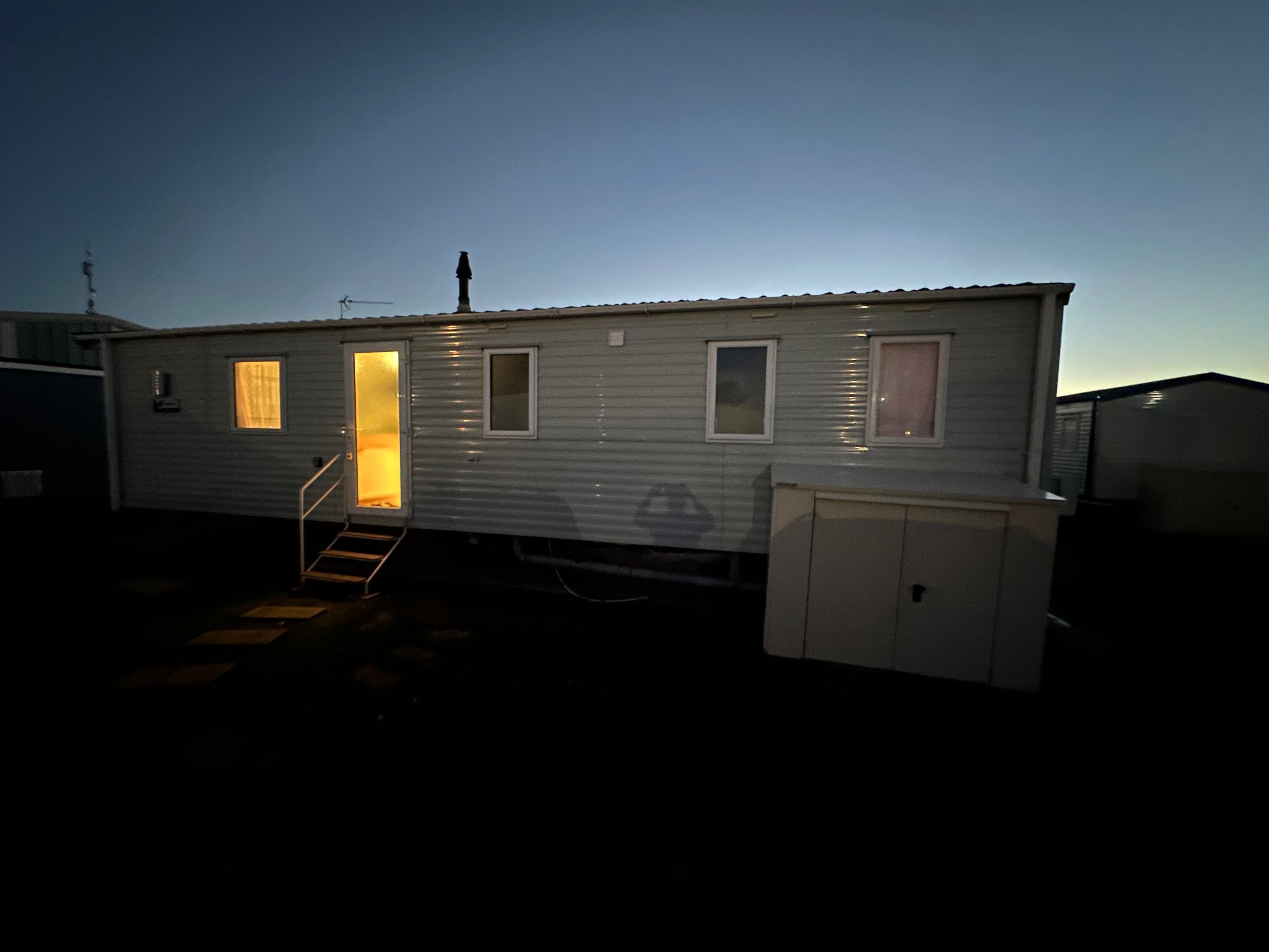 A single-story mobile home with a front door, a small window, and a garage door.