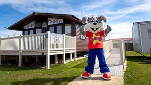 Une mascotte se tient devant un bâtiment sur lequel on peut lire les inscriptions « Artisanat » et « Poterie ».
