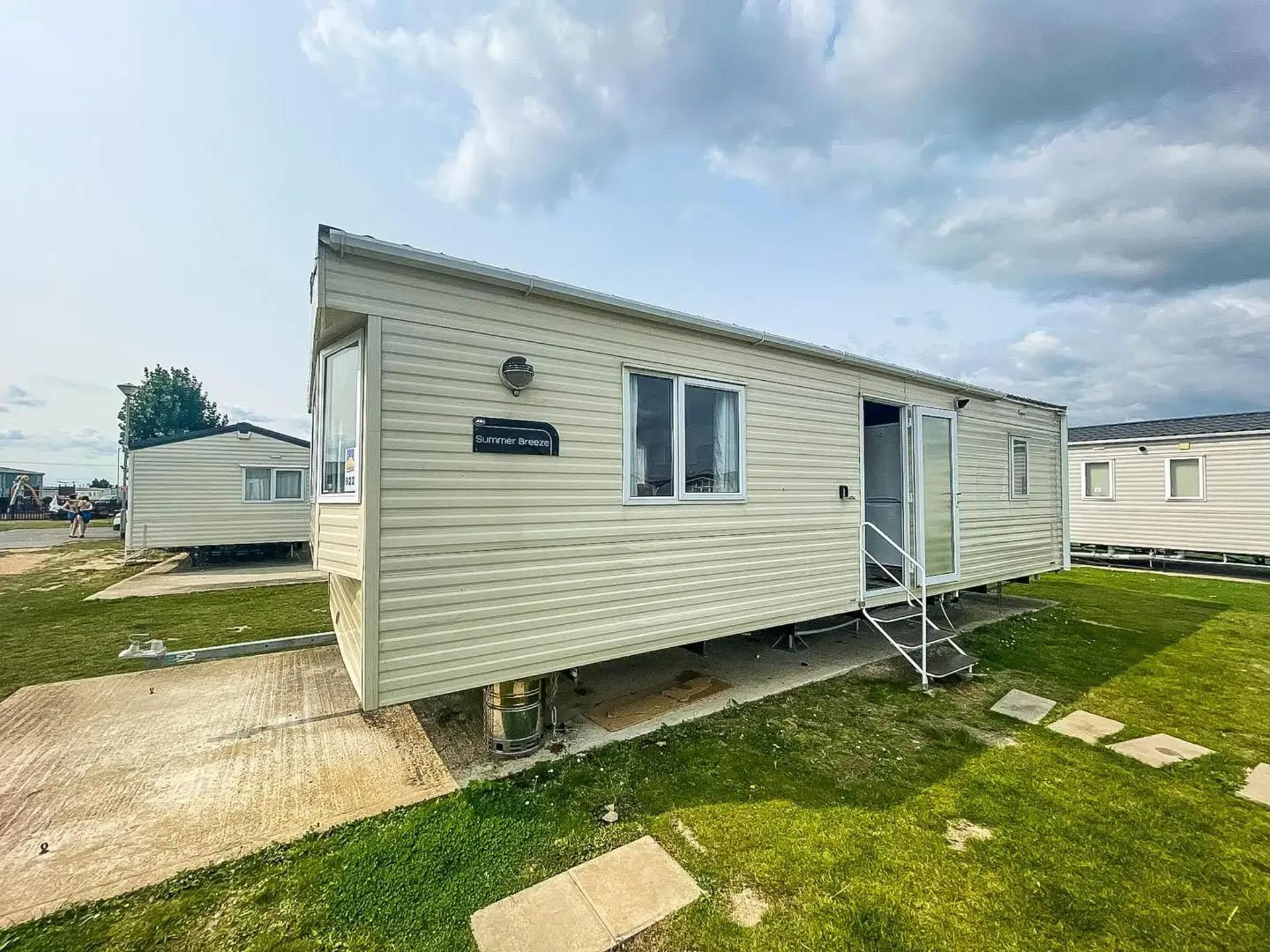 A single-story mobile home with a door, windows, and a nameplate reading 'Summer Breeze.'