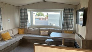 Un intérieur de camping-car confortable, avec un canapé, une table et un téléviseur.