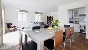 Un salon moderne comprenant un canapé, une table à manger avec des chaises et un coin cuisine avec des placards et des appareils électroménagers.