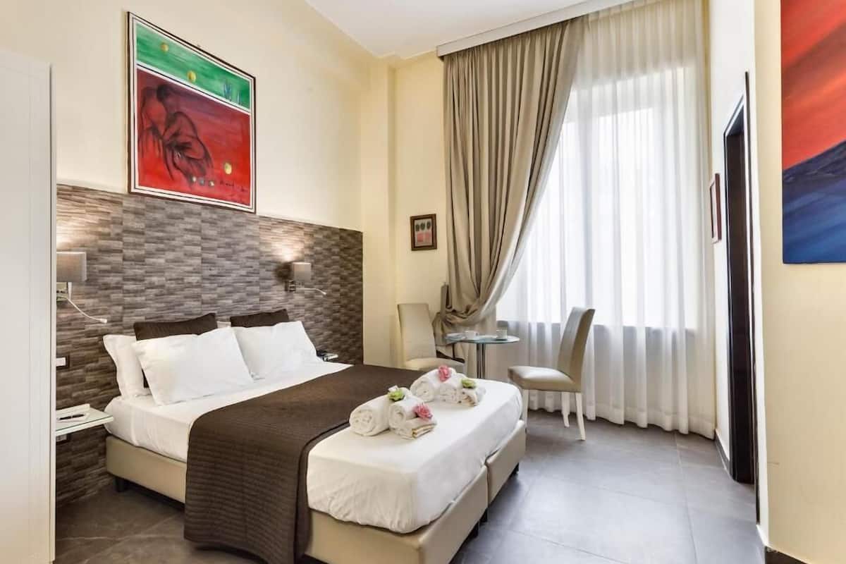 Una habitación de hotel con cama, escritorio, silla y televisión.