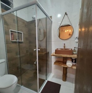 Bathroom features a glass-enclosed shower, sink, and mirror.