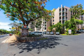 Un hôtel à plusieurs étages, doté d’une façade en pierre, d’un parking et d’un panneau indiquant les différents services proposés, tels que des boutiques et un magasin d’articles de plongée.