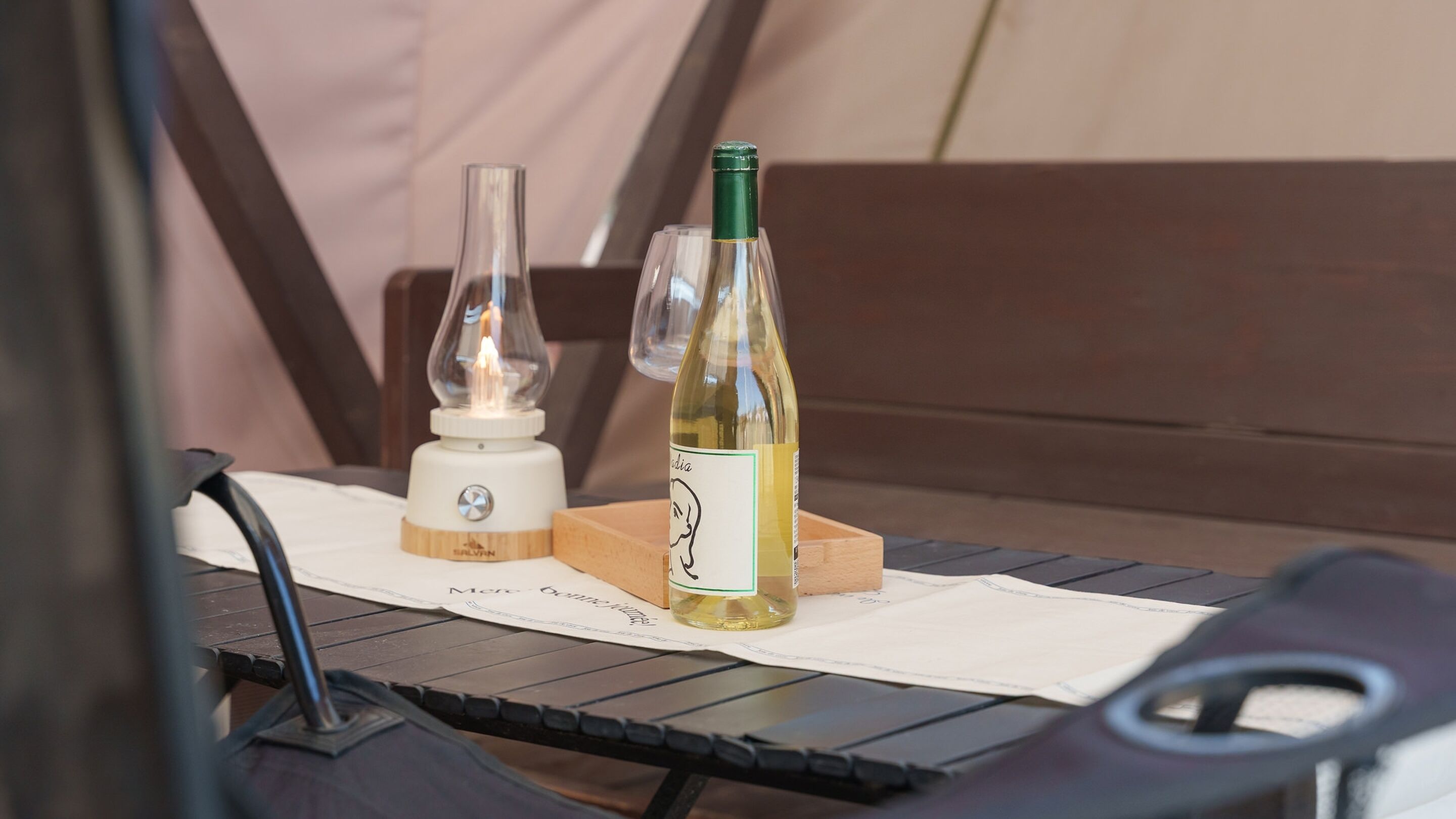 A table with a bottle of wine, a candle, and a small wooden block.
