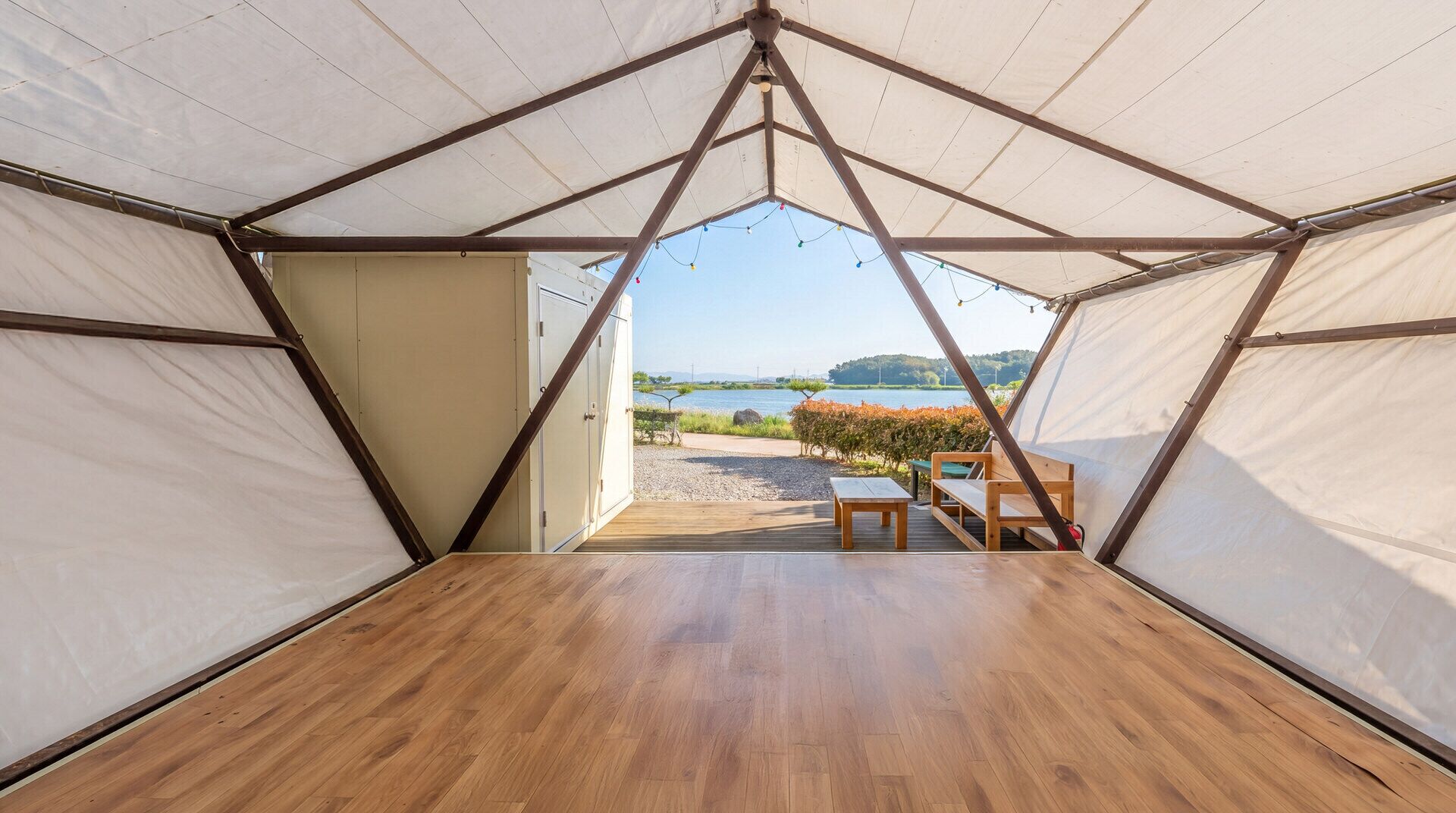 A tent with a wooden floor and a view of a lake.