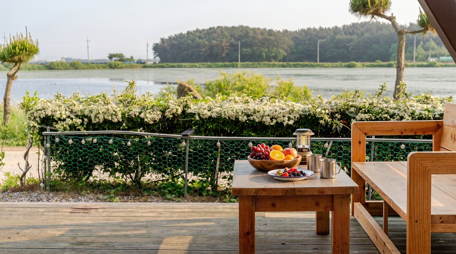 A wooden deck with a table set for a meal, a bowl of fruit, and a lantern.