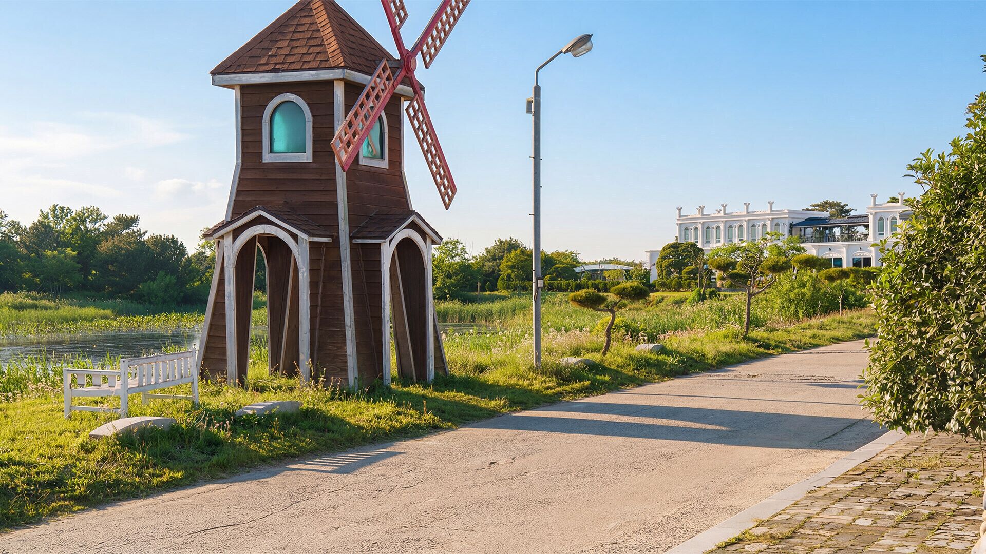 Un molí de vent, un camí pavimentat i un edifici al fons.