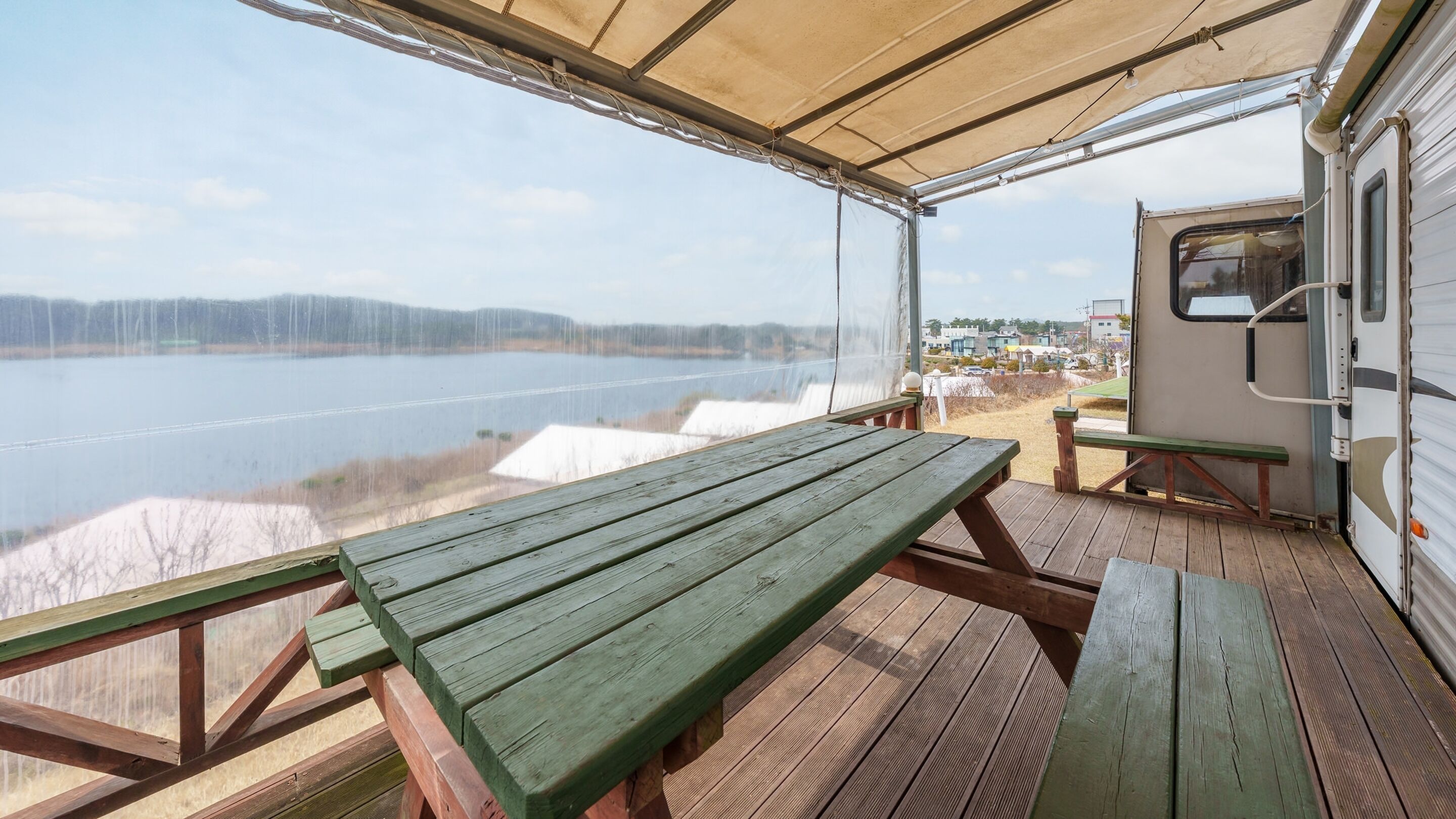 A covered deck with picnic tables overlooking a lake.
