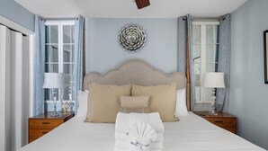 Un lit bien fait, avec une tête de lit, deux tables de chevet avec des lampes et un élément décoratif mural.