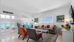 A spacious living room with a large glass table, comfortable seating, and a view of the ocean. - Modern, Stunning & Bright Central Beach Villa (Nassau)