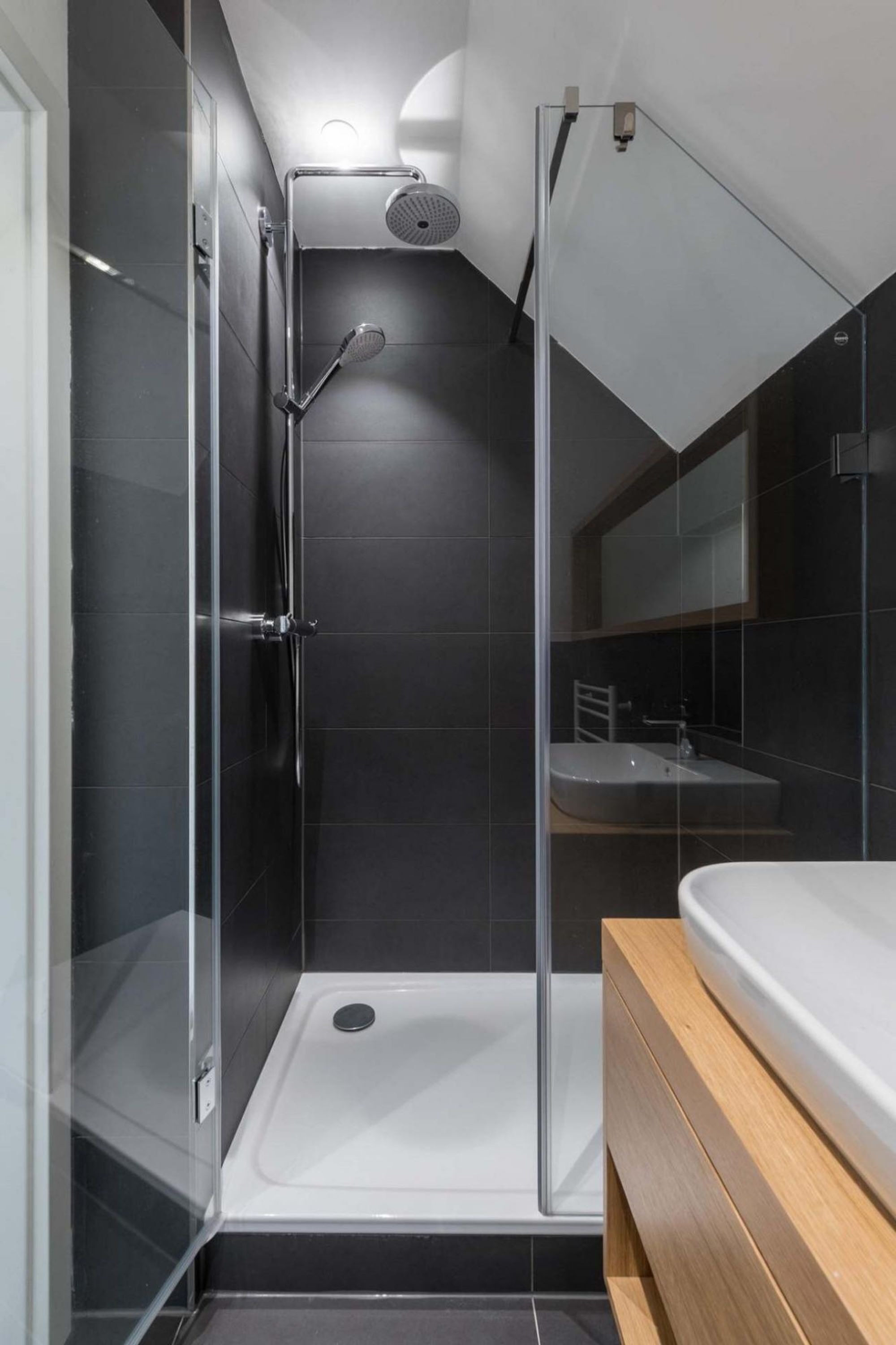 Une salle de bain moderne avec une douche à l’italienne en verre, une baignoire blanche et un meuble-lavabo en bois.