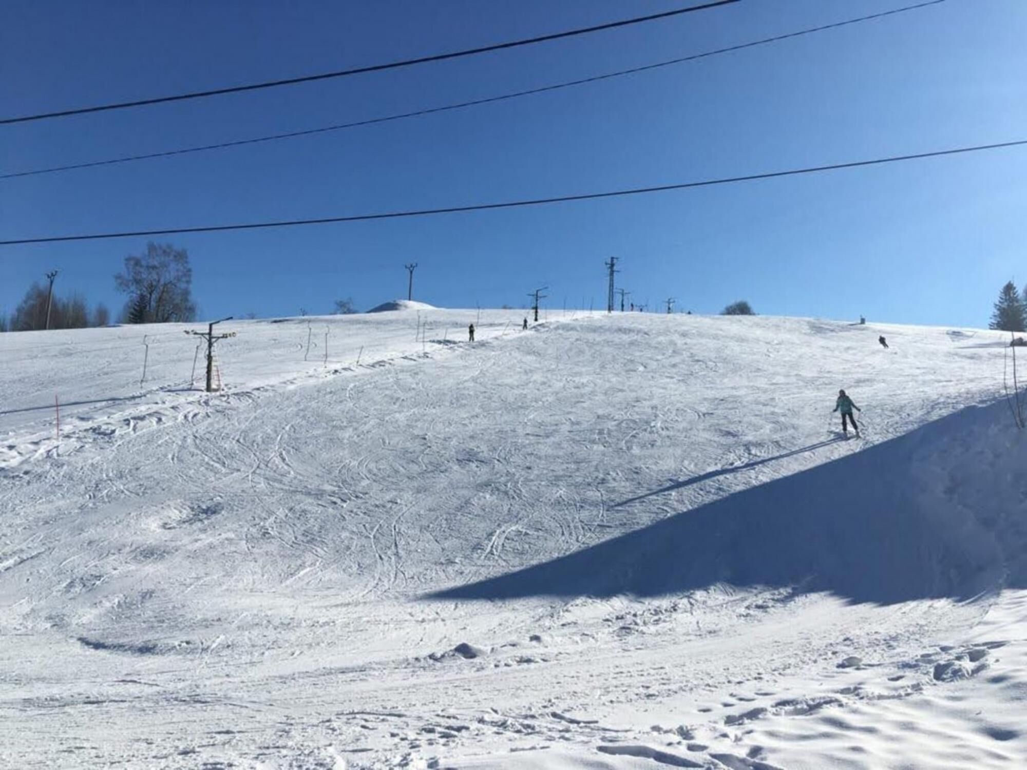 A snowy ski slope with ski lifts and a clear blue sky.