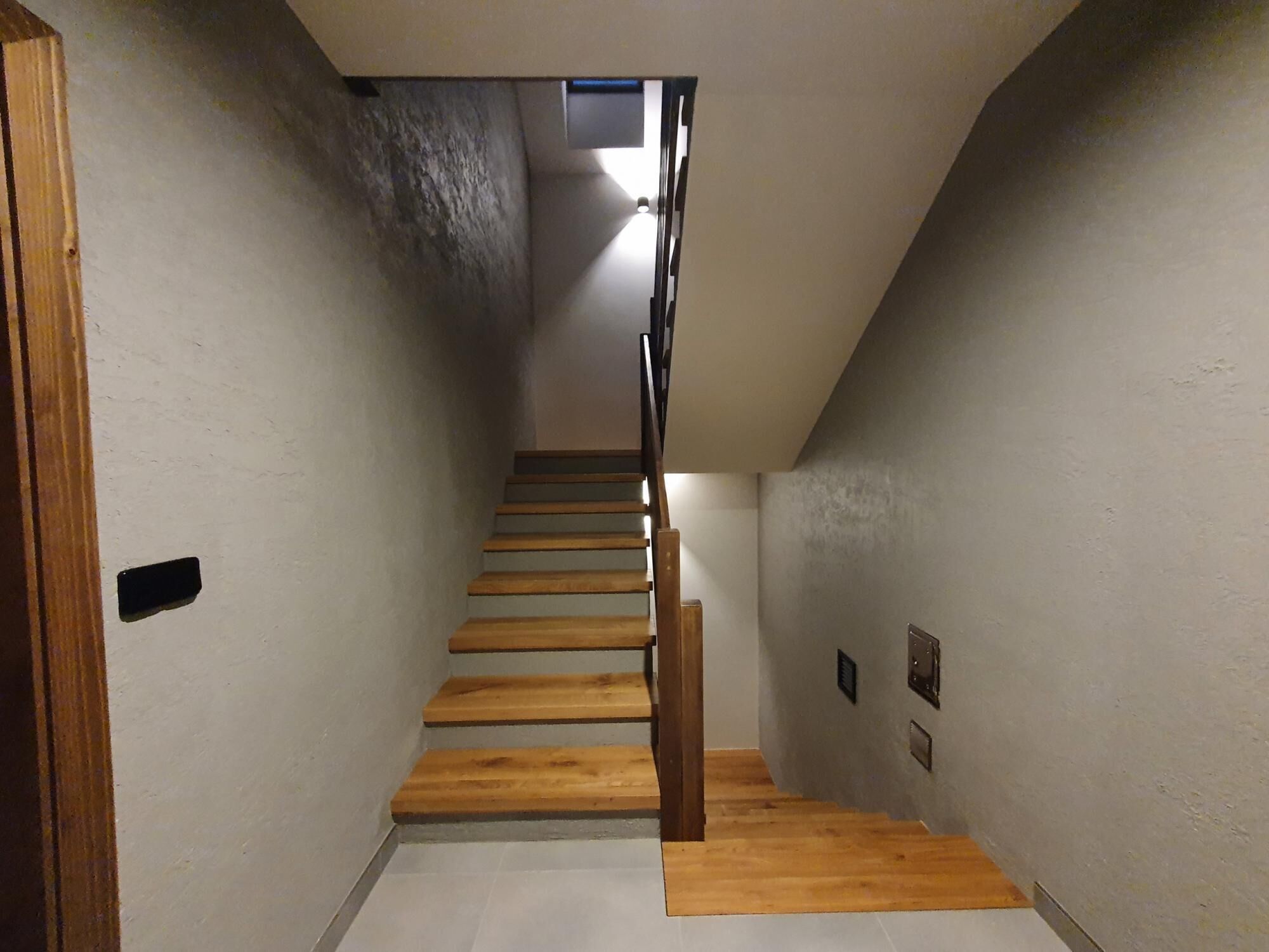 Un couloir étroit avec un escalier en bois menant à un palier.