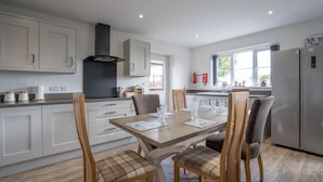 A modern kitchen with white cabinets, a central island, and a dining area with wooden chairs and a table.