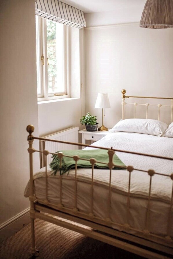 A bedroom with a bed, a nightstand, a lamp, and a window with curtains.