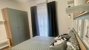 A bedroom with a bed, a wardrobe, a bedside table, a lamp, and a window with curtains. - Walking distance from Vomero, metro within walking distance in area full of clubs.  (Napoli)