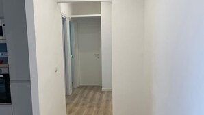 A hallway with wooden flooring and white walls, leading to a kitchen area with appliances. - Walking distance from Vomero, metro within walking distance in area full of clubs.  (Napoli)