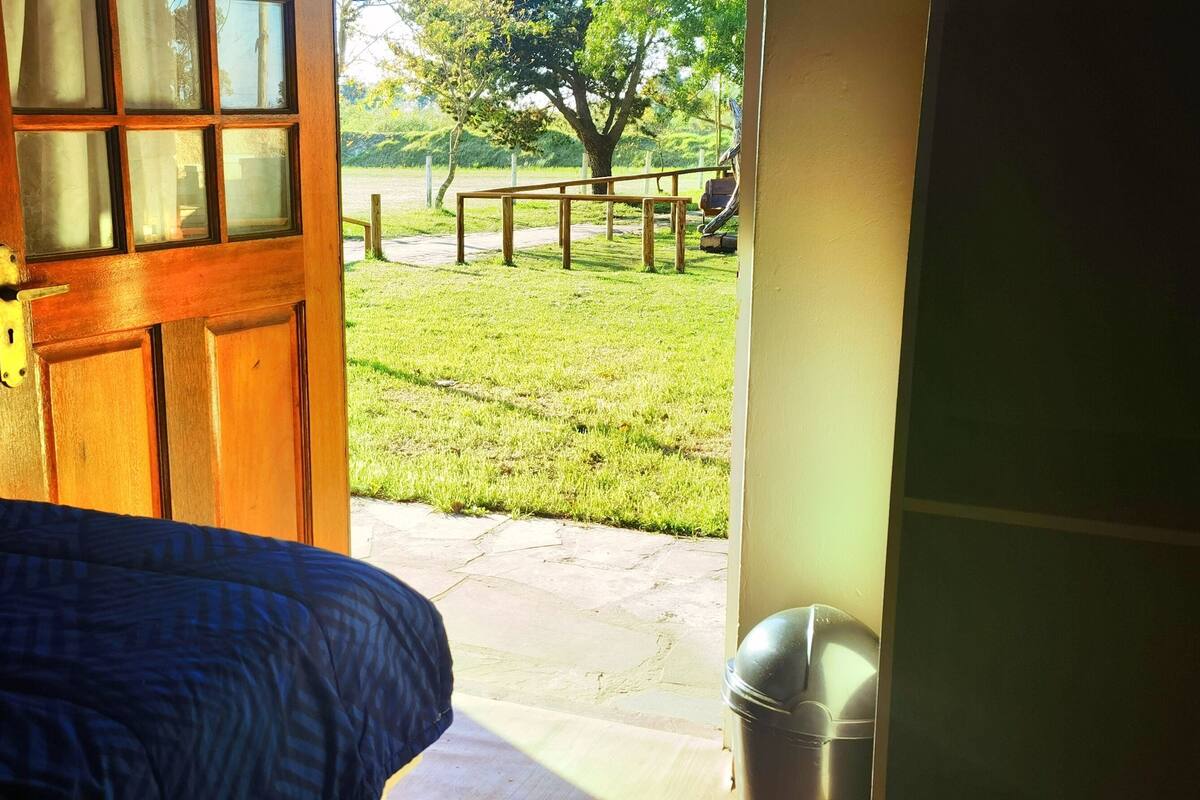 Un dormitorio con una puerta de madera que da a un espacio exterior con césped y una banca.