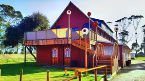 Un bâtiment en bois rouge avec un escalier, une clôture en bois et un ciel dégagé.