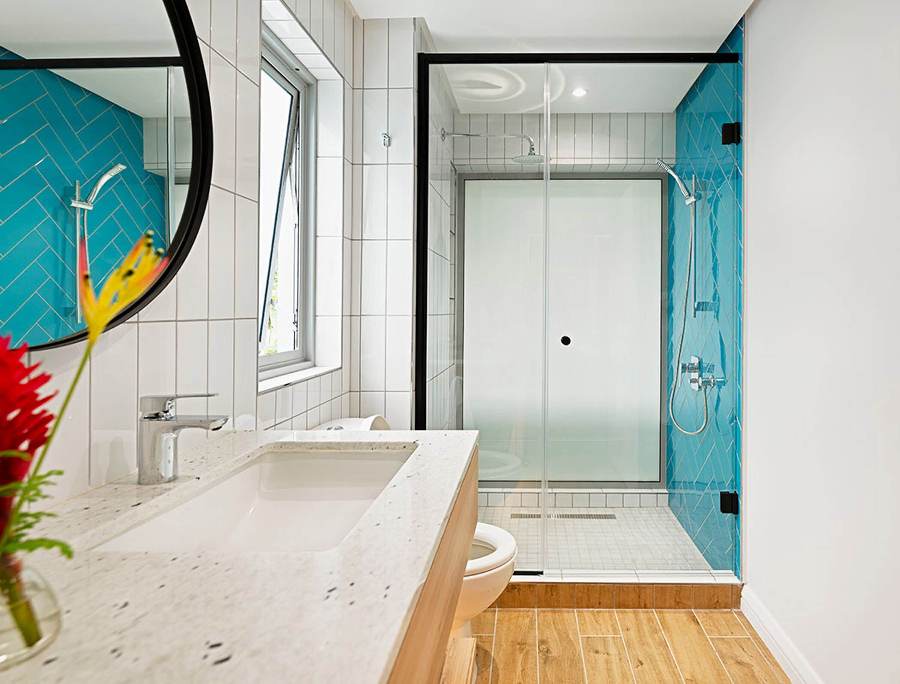 A modern bathroom with a glass-enclosed shower, a white sink, and a mirror.