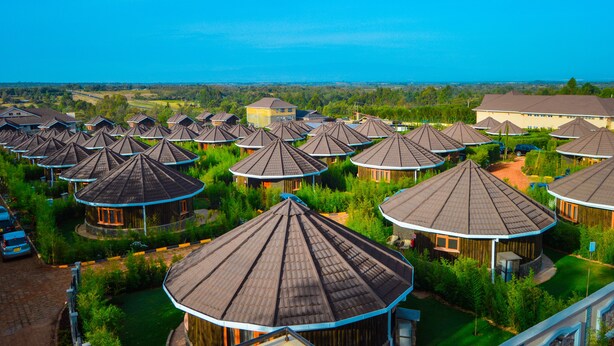 A cluster of dome-shaped buildings with a central courtyard, surrounded by greenery and a clear blue sky.